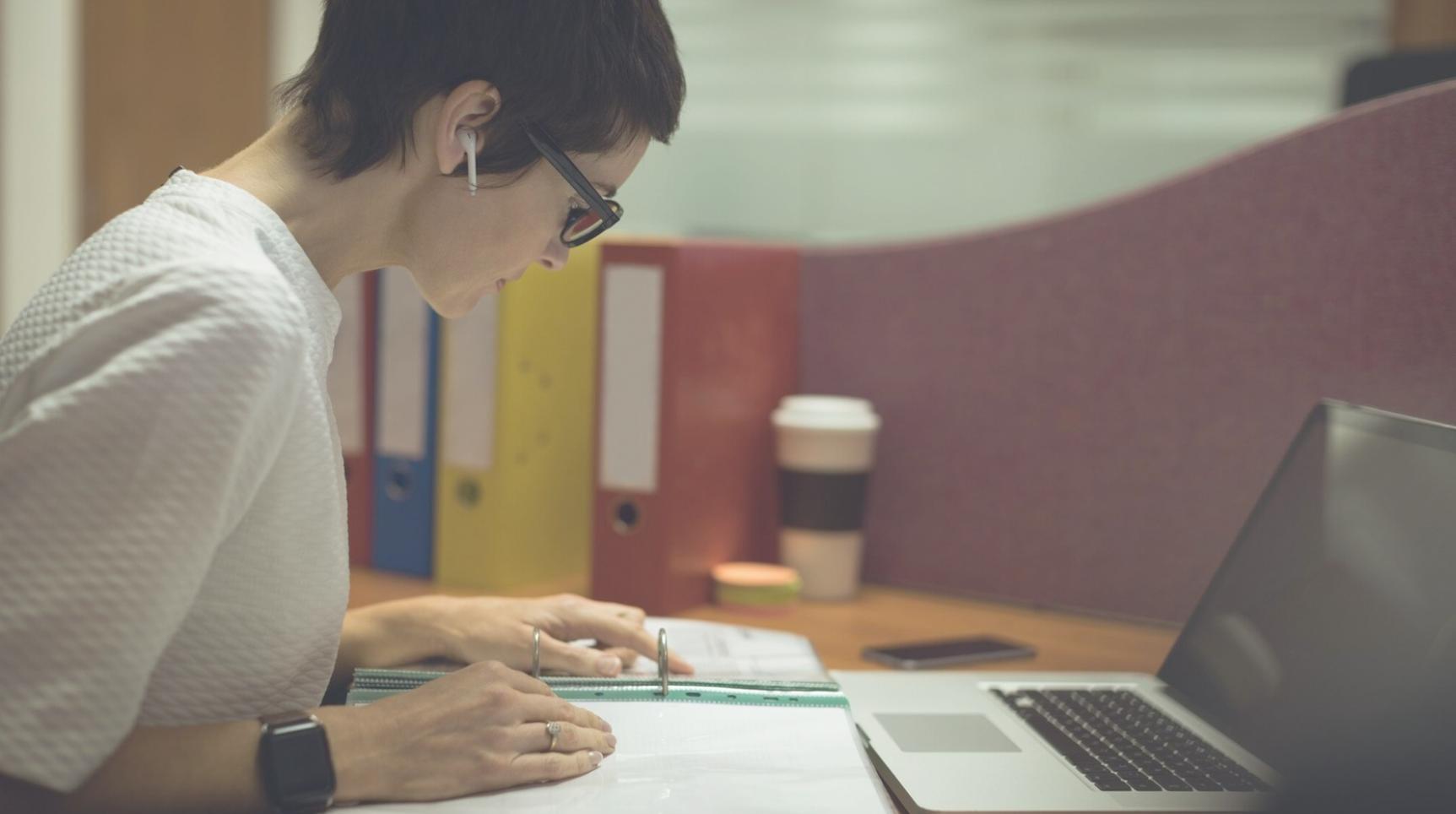 Persona trabajando con calculadora y documentos financieros en escritorio ordenado